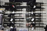 AR-15 style rifles are displayed at a story, they hang on the wall with price tags on them.