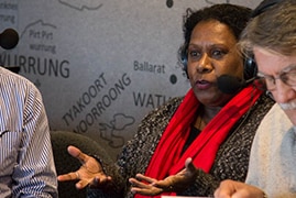 Two men listen as a woman talks. All wear radio headsets with microphones.