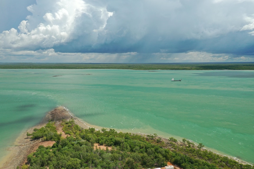 Una foto de dron de una pequeña rampa, con mares claros y exuberante vegetación.  El cielo es azul.