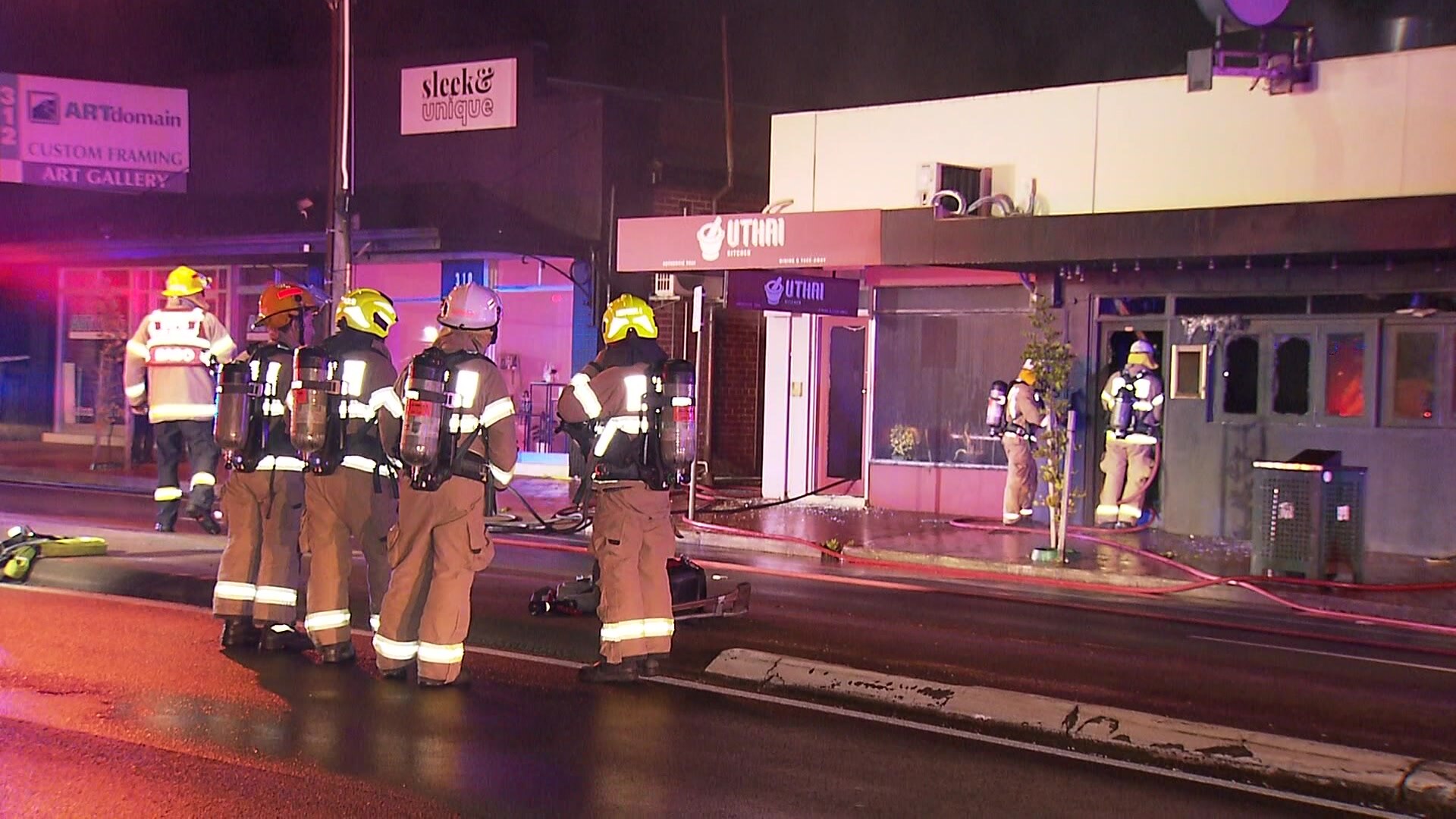 Four firefighters standing infront of a burnt out business 