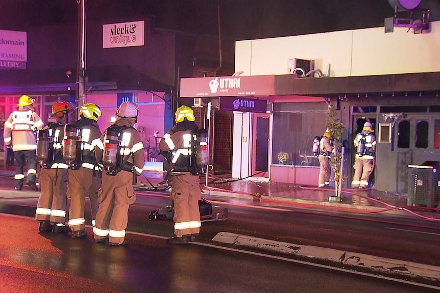 Four firefighters standing infront of a burnt out business 