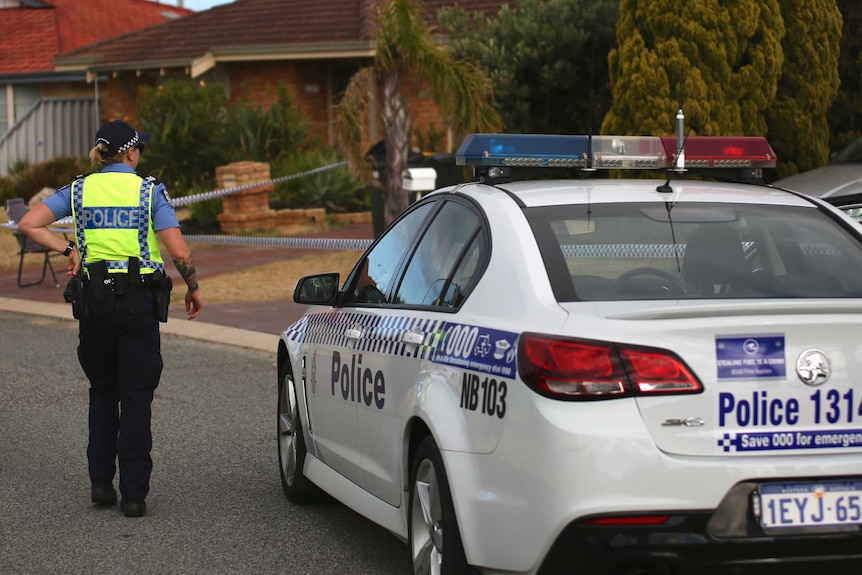 A police officer and a police car out the front of a suburban house.