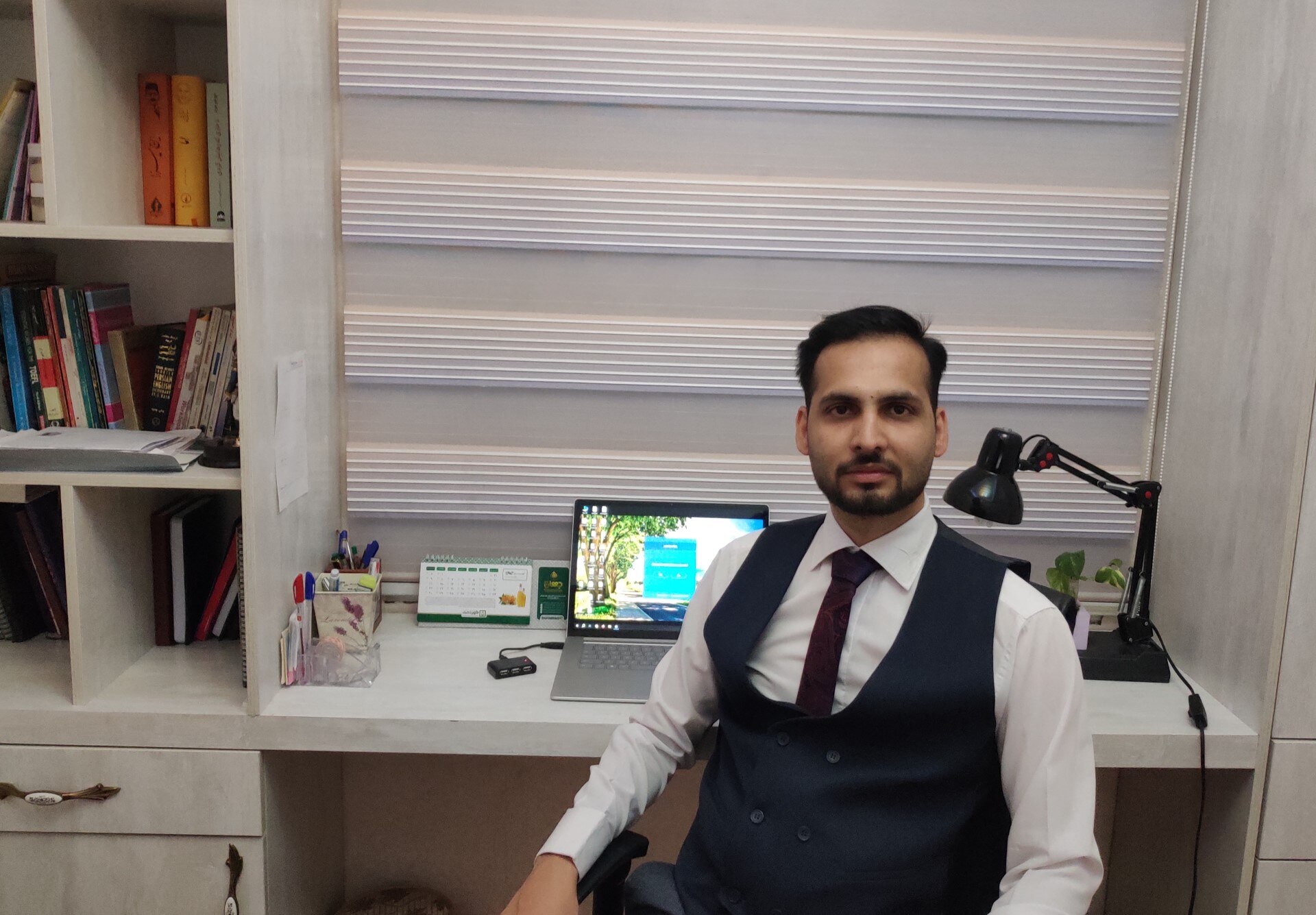 A young man in suit sitting in front of his desk