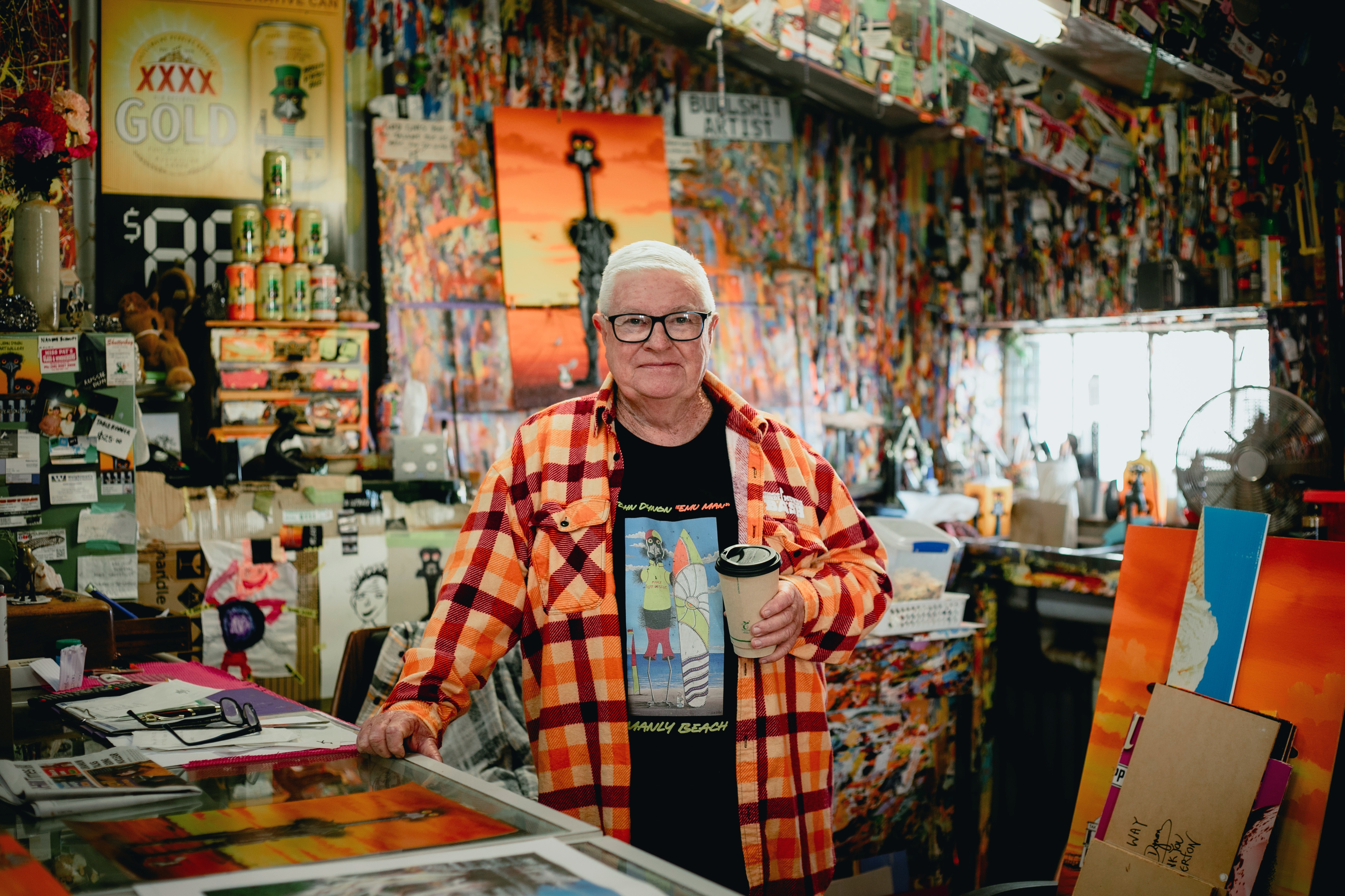 Artist John Dynon in his Silverton gallery and studio, surrounded by colourful paintings.