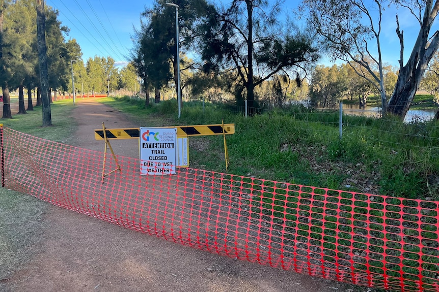 Barriers and signage barricade off a riverside walking path