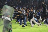 Soccer fans enter the pitch during a clash between supporters at Kanjuruhan Stadium in Malang.