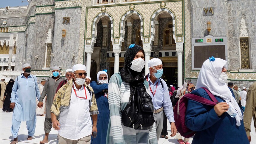 Muslim worshippers wearing medical masks walk near the Grand Mosque in the Saudi Arabian city of Mecca.