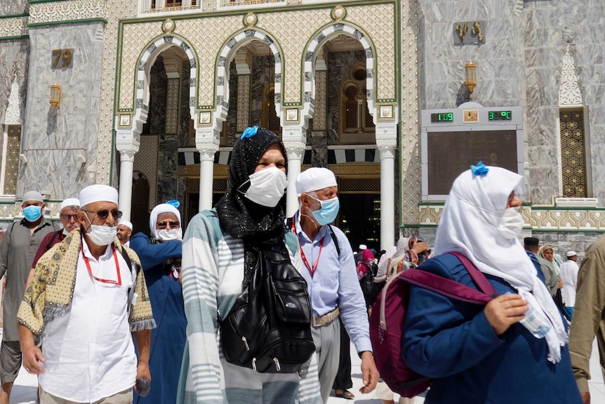 Muslim worshippers wearing medical masks walk near the Grand Mosque in the Saudi Arabian city of Mecca.