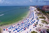 A drone shot of lots of blue umbrellas on a beach