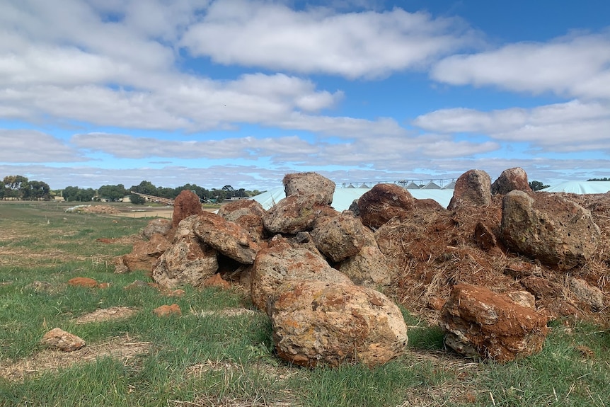 A pile of rocks and earth sits on a grassy field.