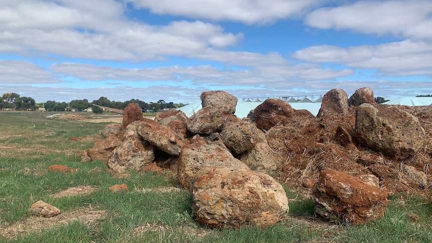 A pile of rocks and earth sits on a grassy field.