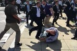 A member of Turkish President Erdogan's security detail kicks a protester who is laying on the ground holding his head.