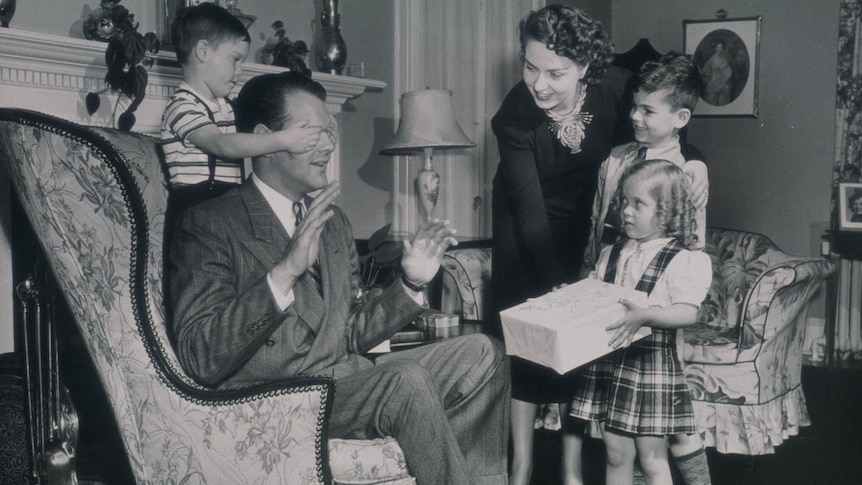 A father being given a gift by his daughter.