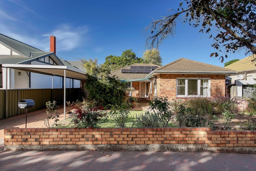 A low brick wall fronts a modest brick home with a small front garden.