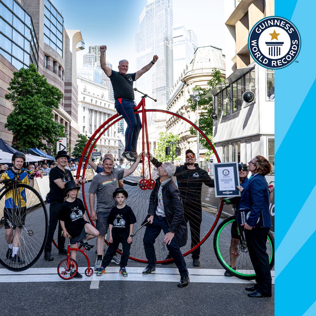 A huge penny-farthing and a tiny one, surrounded by supporters in London.