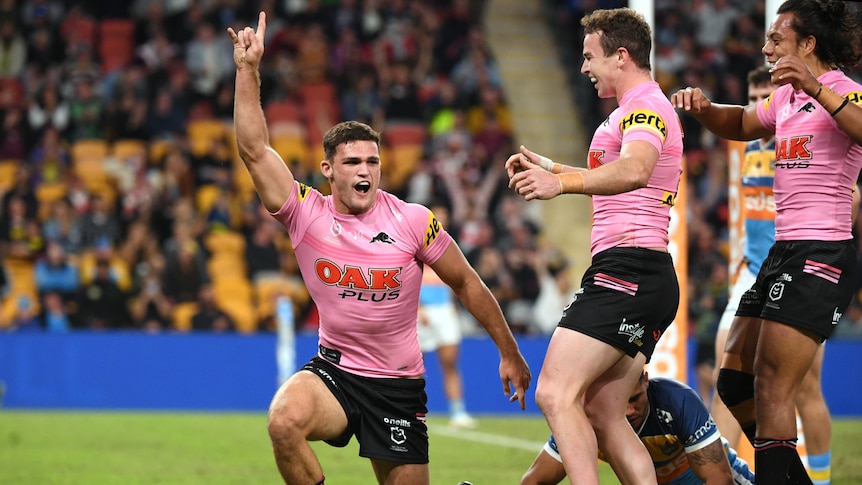 Nathan Cleary raises a finger in the air and shouts as his Penrith Panthers teammates join him to celebrate a try.