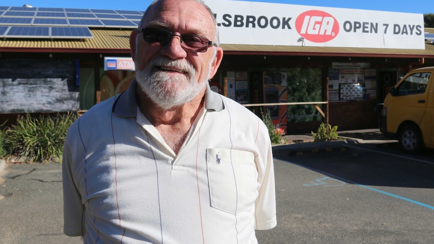 A mid shot of Bullsbrook resident Paddy Mays posing for a photo in a polo shirt and smiling while standing outside an IGA store.