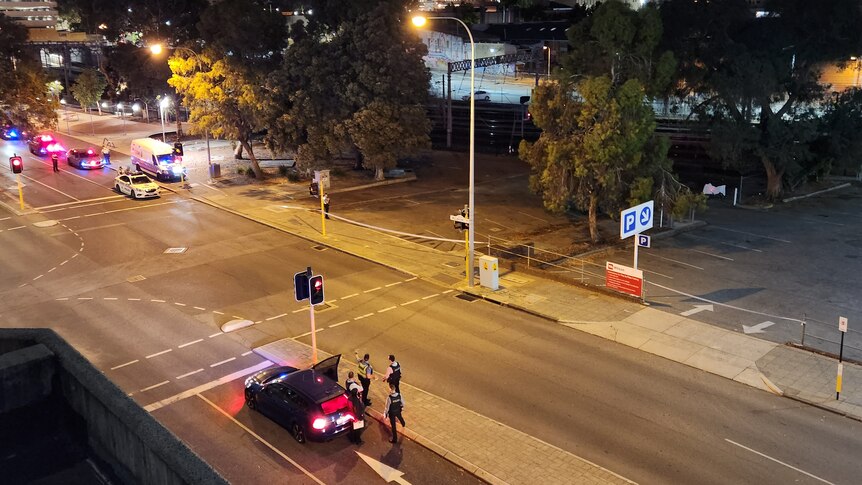 A high and wide shot at night showing police officers and vehicles on Wellington Street in the Perth CBD.