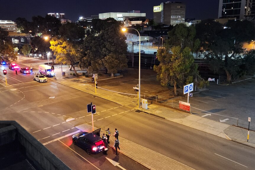 A high and wide shot at night showing police officers and vehicles on Wellington Street in the Perth CBD.