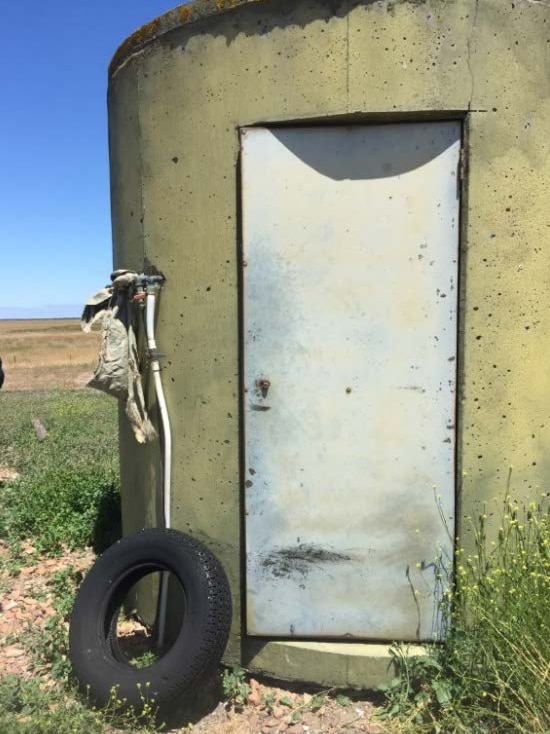 The outside of an old water tank with a door on it that is closed