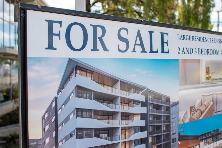 Sign advertising apartments for sale in Brisbane, with apartment block in background.