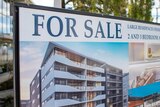 Sign advertising apartments for sale in Brisbane, with apartment block in background.