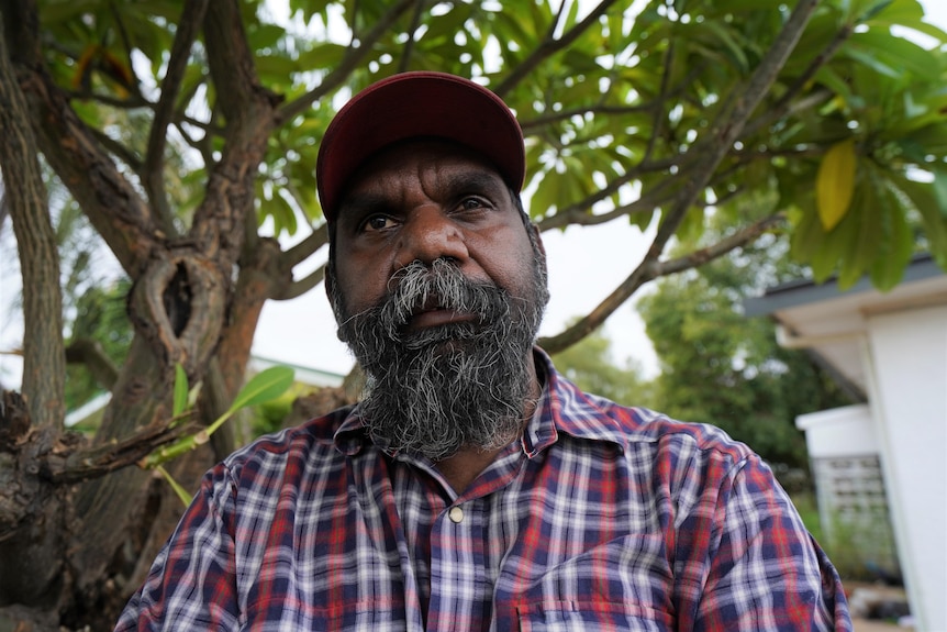 Indigenous man in checkered shirt staring at camera