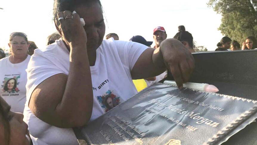 Woman weeps over a memorial plaque