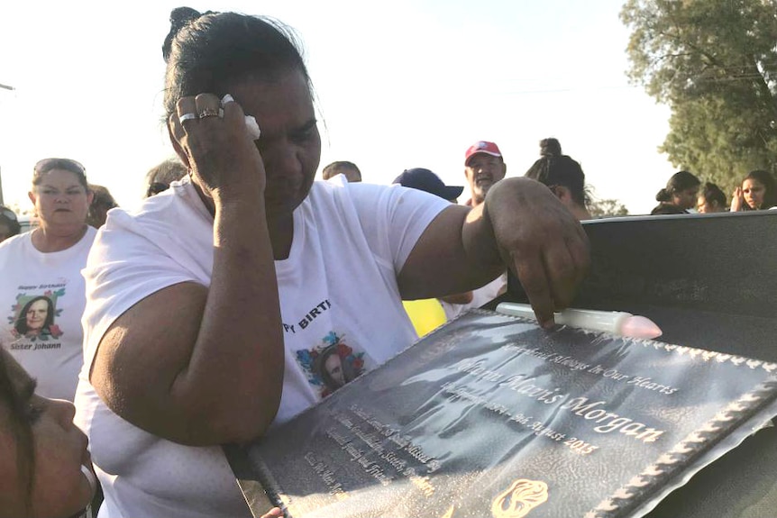 Woman weeps over a memorial plaque
