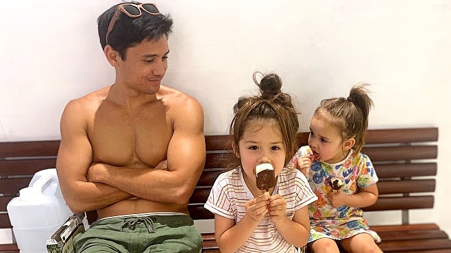 Seiji Armstrong sitting cross-armed with his two daughters in a story about why kids can prefer one parent and what to do.