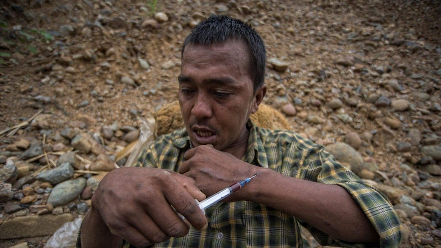 A drug addict shoots heroin at the jade mining site in Myanmar