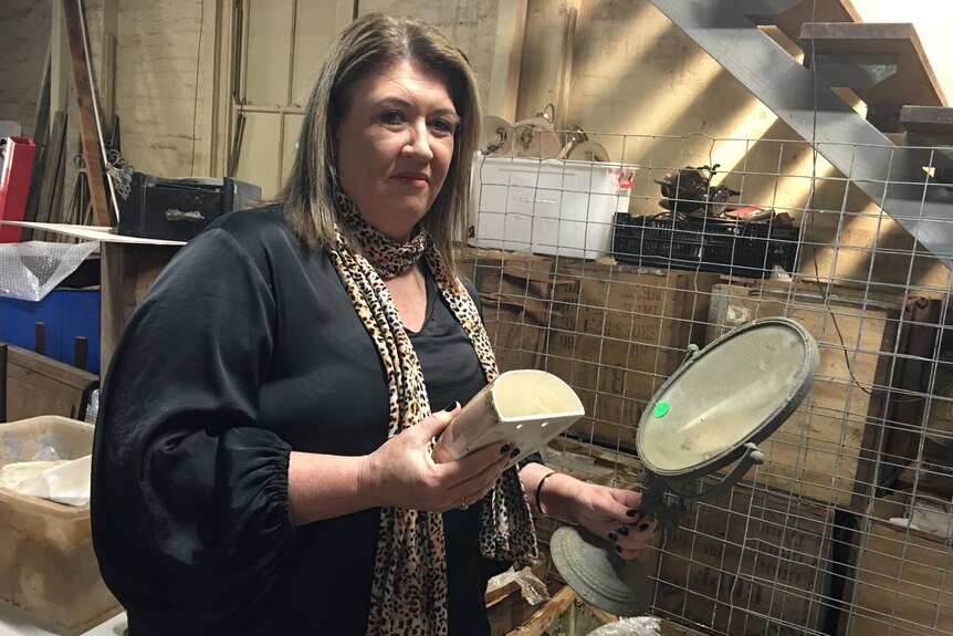 A woman holding small antique mirror and collectibles.