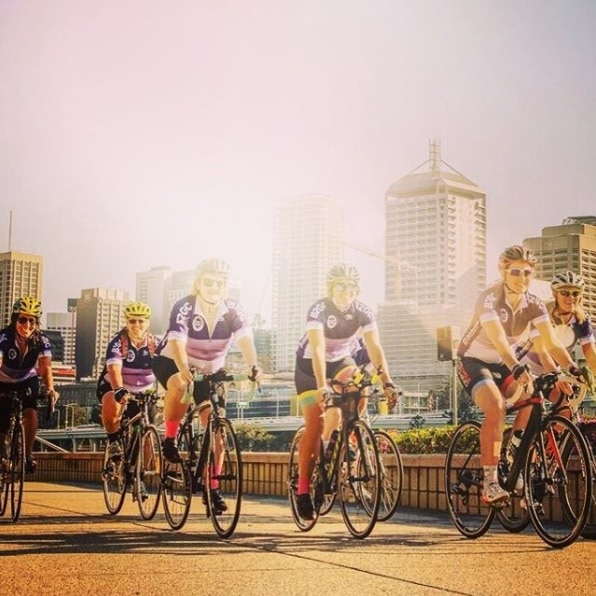 A group of women ride bikes early in the morning in Brisbane.