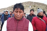 A man  bows his head solemnly as he stands with other relatives of gold miners who are trapped in a Peruvian gold mine