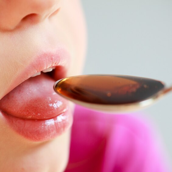 Child taking liquid medicine from a spoon