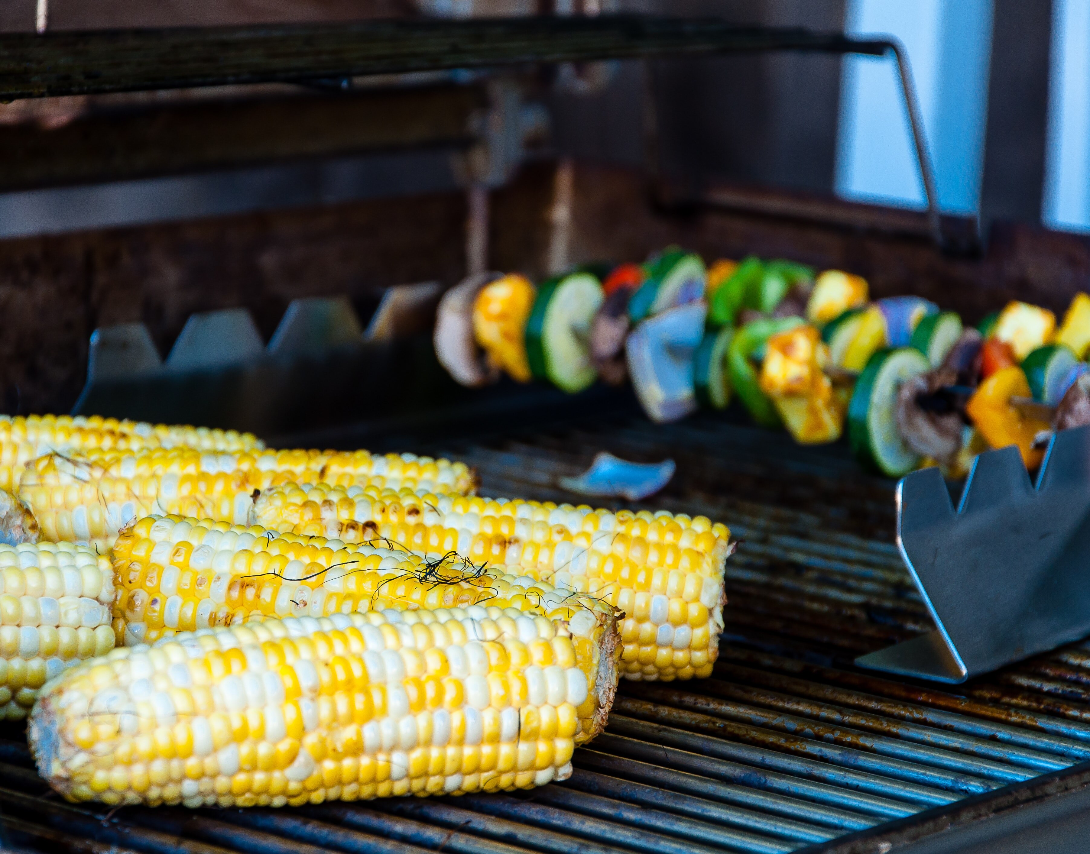 Corn and vegetable kebabs on a BBQ grill.