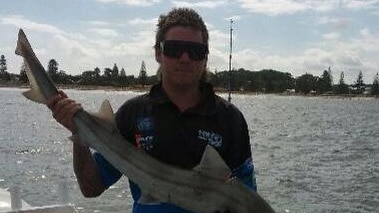 Jordan Fissioli holding a large fish while standing in the back of a boat in a river.