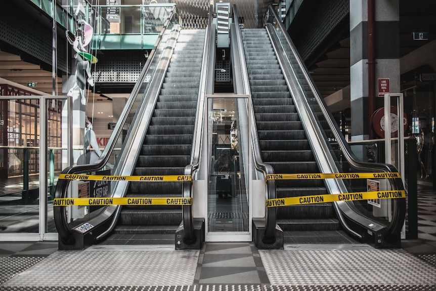 Escalators are closed off with yellow tape reading 'caution'.