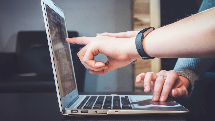 Two people look at a laptop screen for a story about online harassment and how to speak up about it when you observe it.