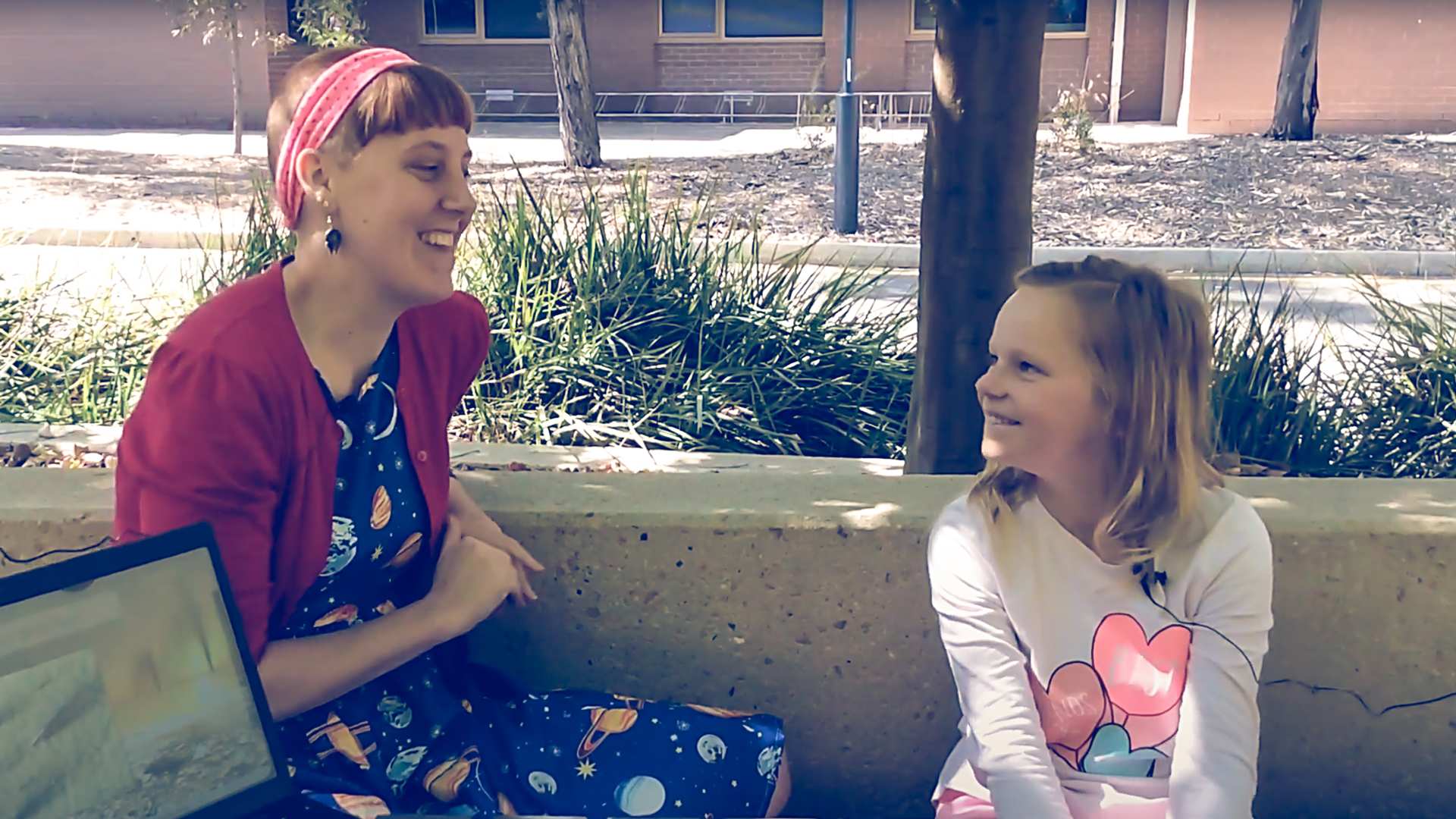 A woman and a girl sitting on a bench talking.