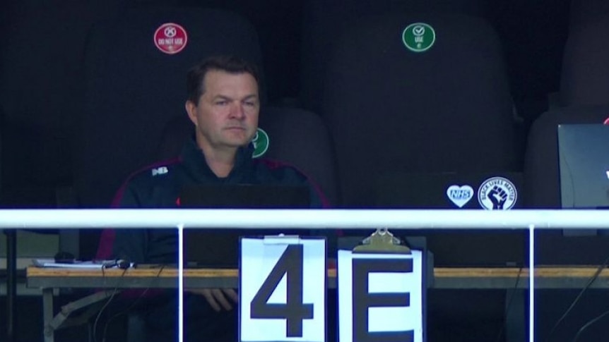 A team analyst sits on a balcony overlooking a cricket ground, with signs saying "4"and "E".