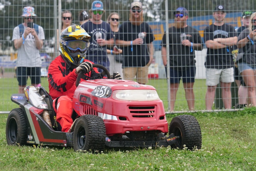 A person racing a ride on lawn mower