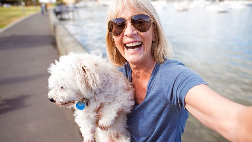 An older woman takes a selfie photo with her dog.