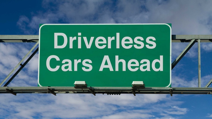 A green and white sign above a road saying 'driverless cars ahead'