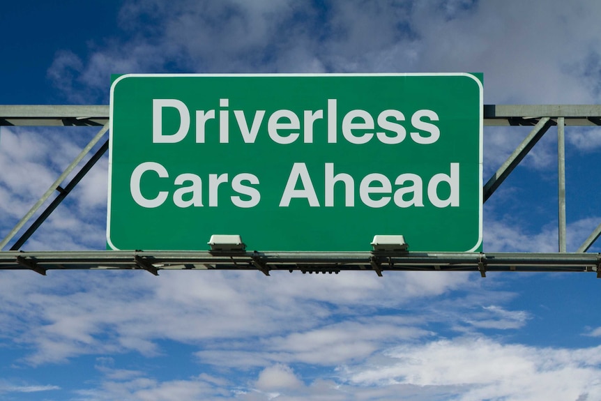 A green and white sign above a road saying 'driverless cars ahead'