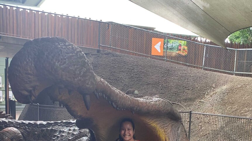University student Jeena Weber Langstaff sitting inside a fake crocodile mouth, smiling