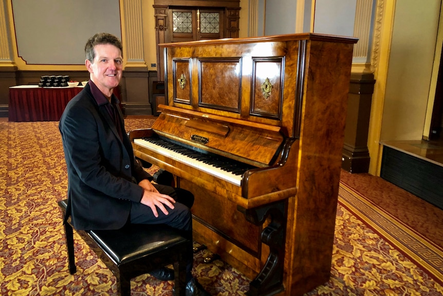 Pianist Dr Peter Butler sitting at the old piano.