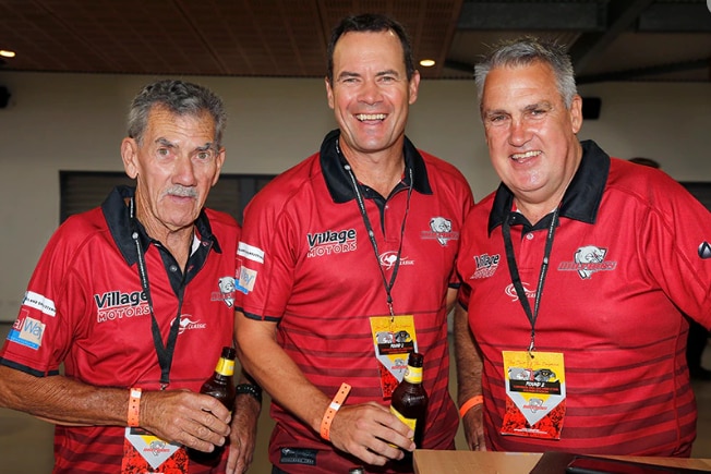 three men wearing redcliffe dolphins polo shirts smile at the camera