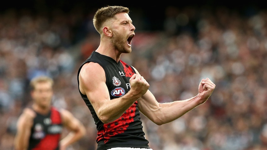 An Essendon AFL player pumps both his fists as he celebrate a goal against Collingwood.