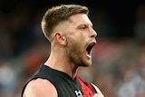 An Essendon AFL player pumps both his fists as he celebrate a goal against Collingwood.